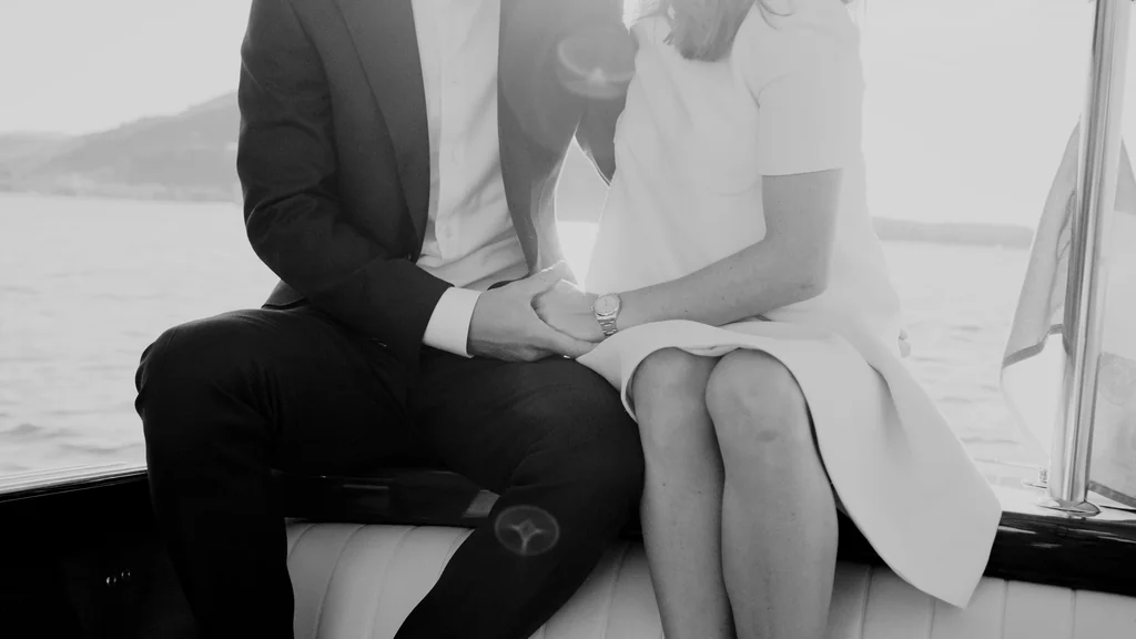 Detailaufnahme der ineinandergelegten Hände des Brautpaars am Heck des Bootes.