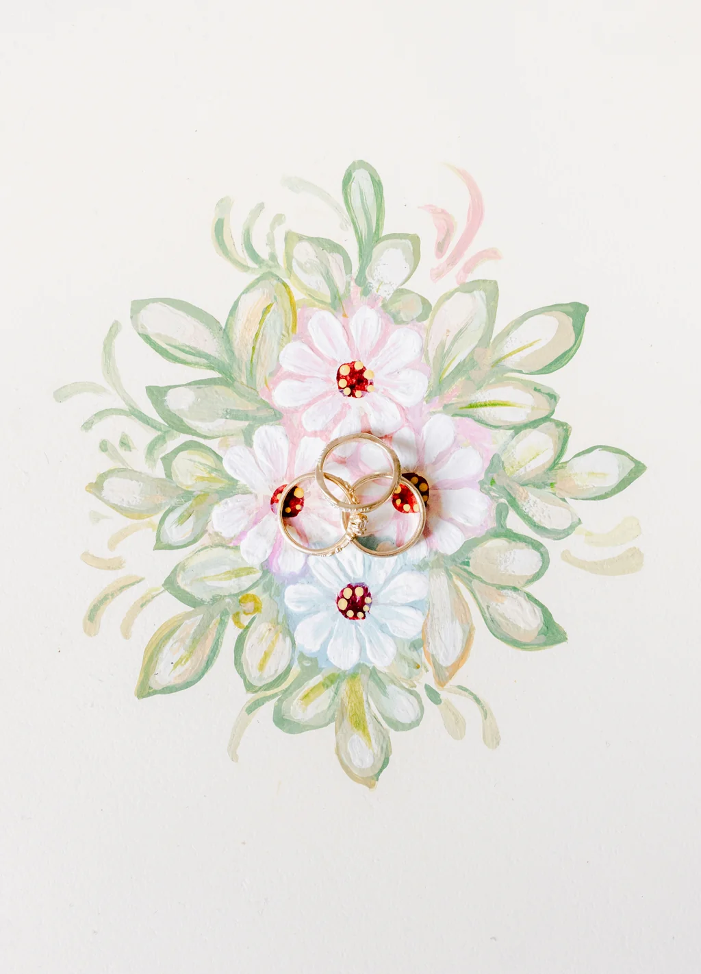 Detailaufnahme der Ringe auf einem handgezeichneten floralen Motiv in Pastelltönen.