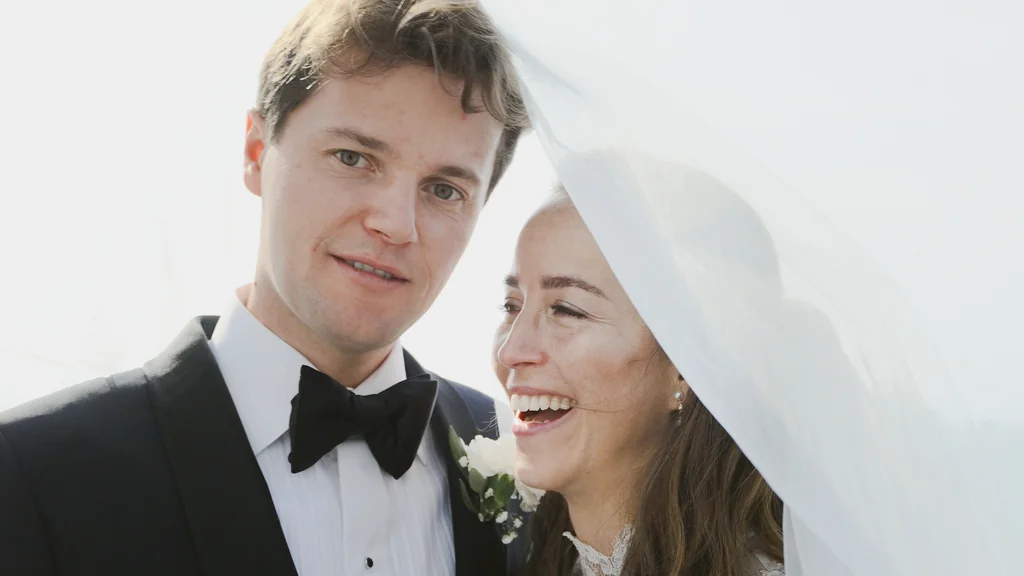 Ein glückliches, lachendes Brautpaar während des Shootings unter einem Schleier.