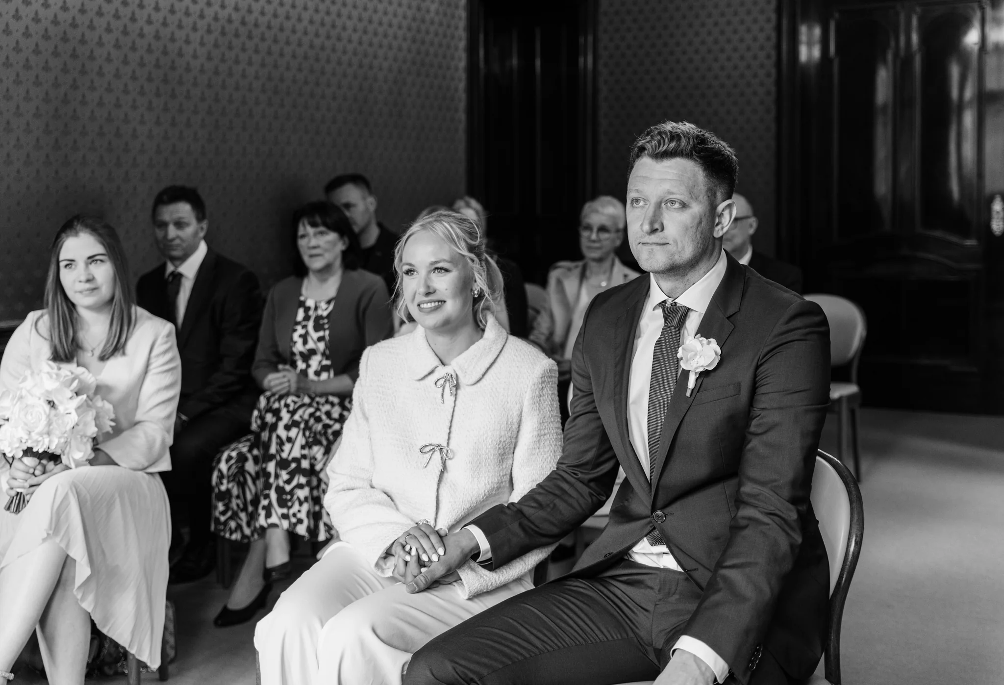 Schwarz-Weiß-Aufnahme der Hochzeitsgesellschaft und des Brautpaars während der Traurede in der Villa Weigang.