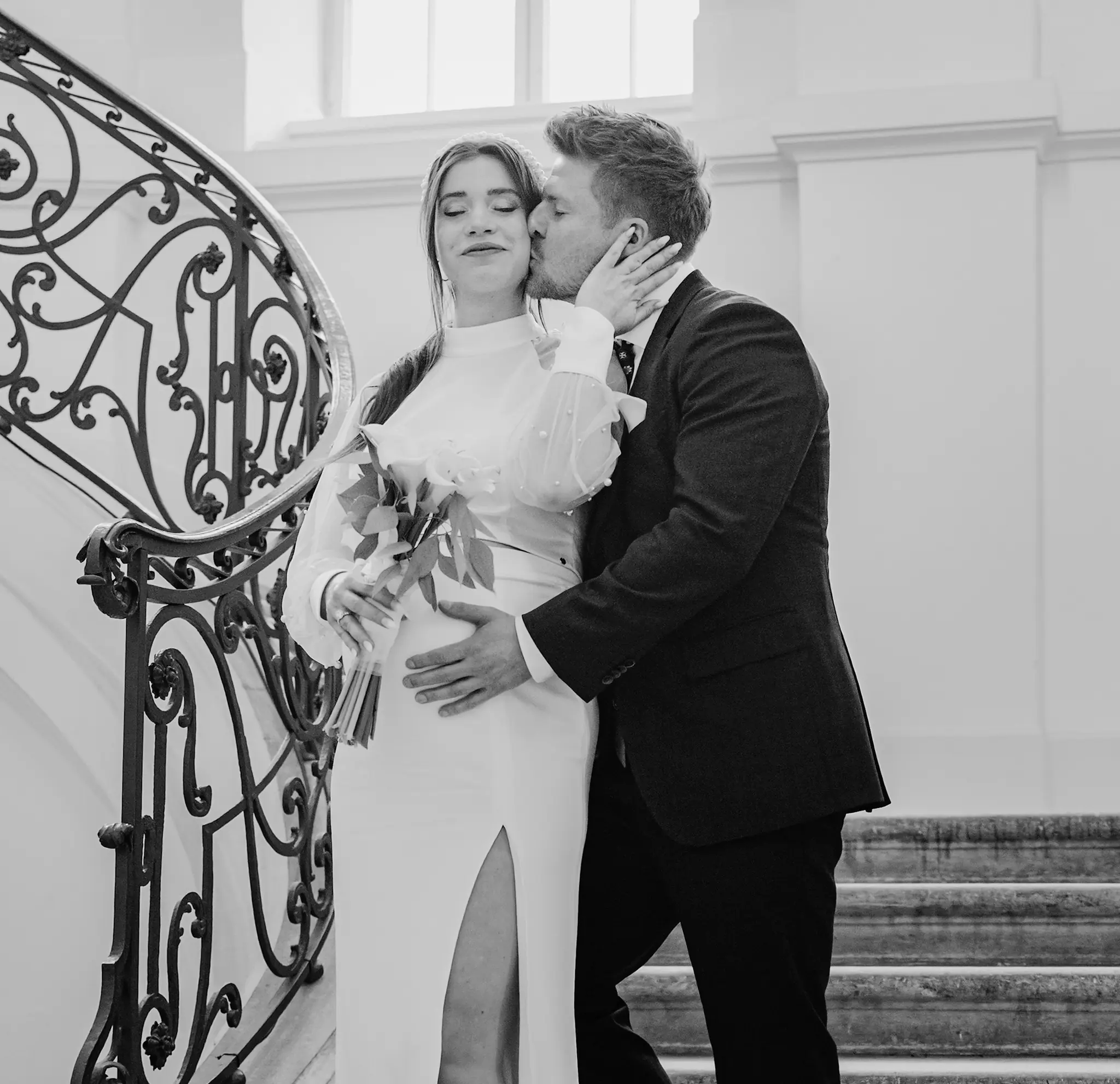Ein emotionaler Schwarz-Weiß-Moment: Der Bräutigam küsst die Braut innig auf der Treppe beim Paarshooting im Landhaus Dresden, als Kontrast zum Standesamt Goetheallee.